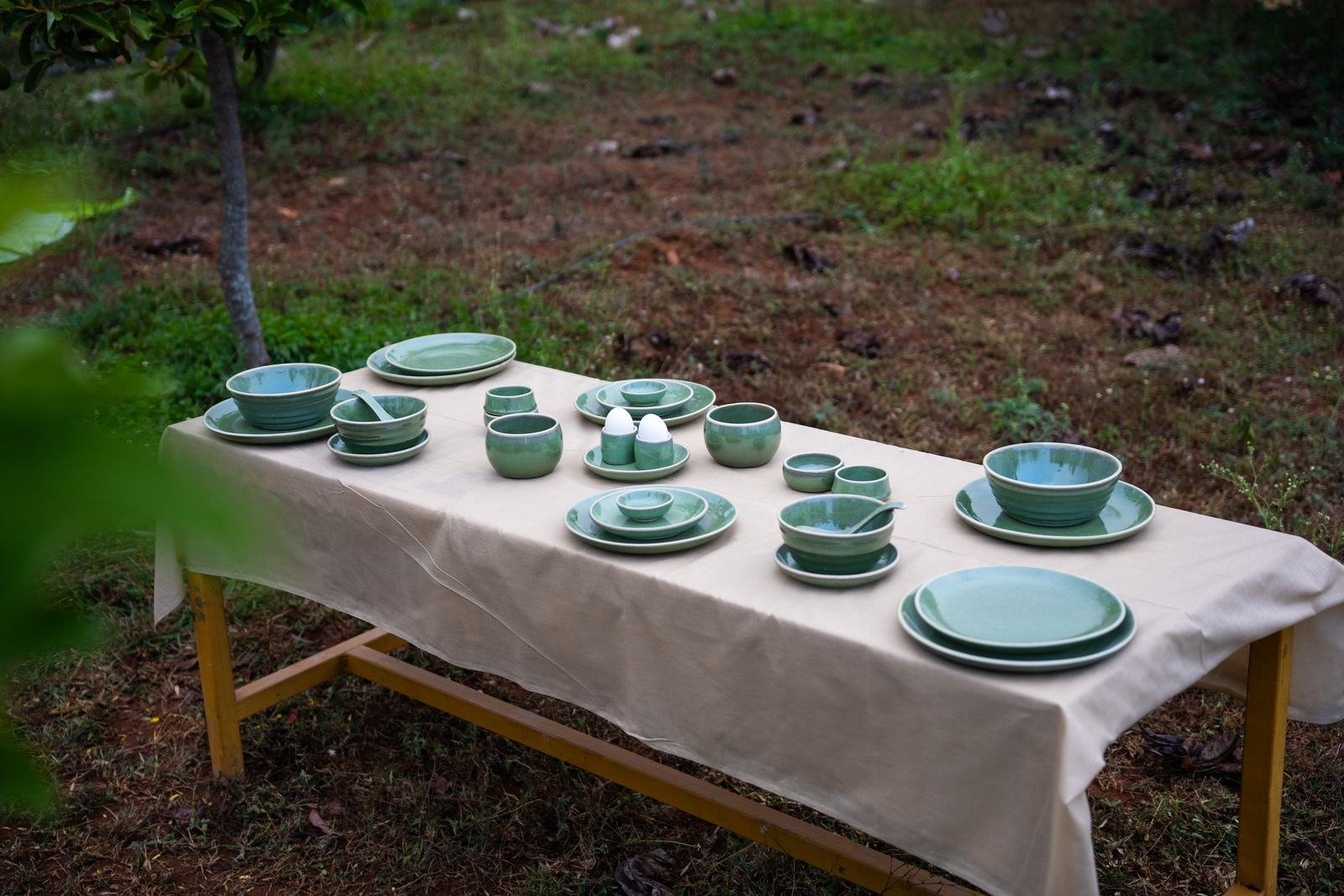 Sage green Nugu tableware set on a long table outdoors