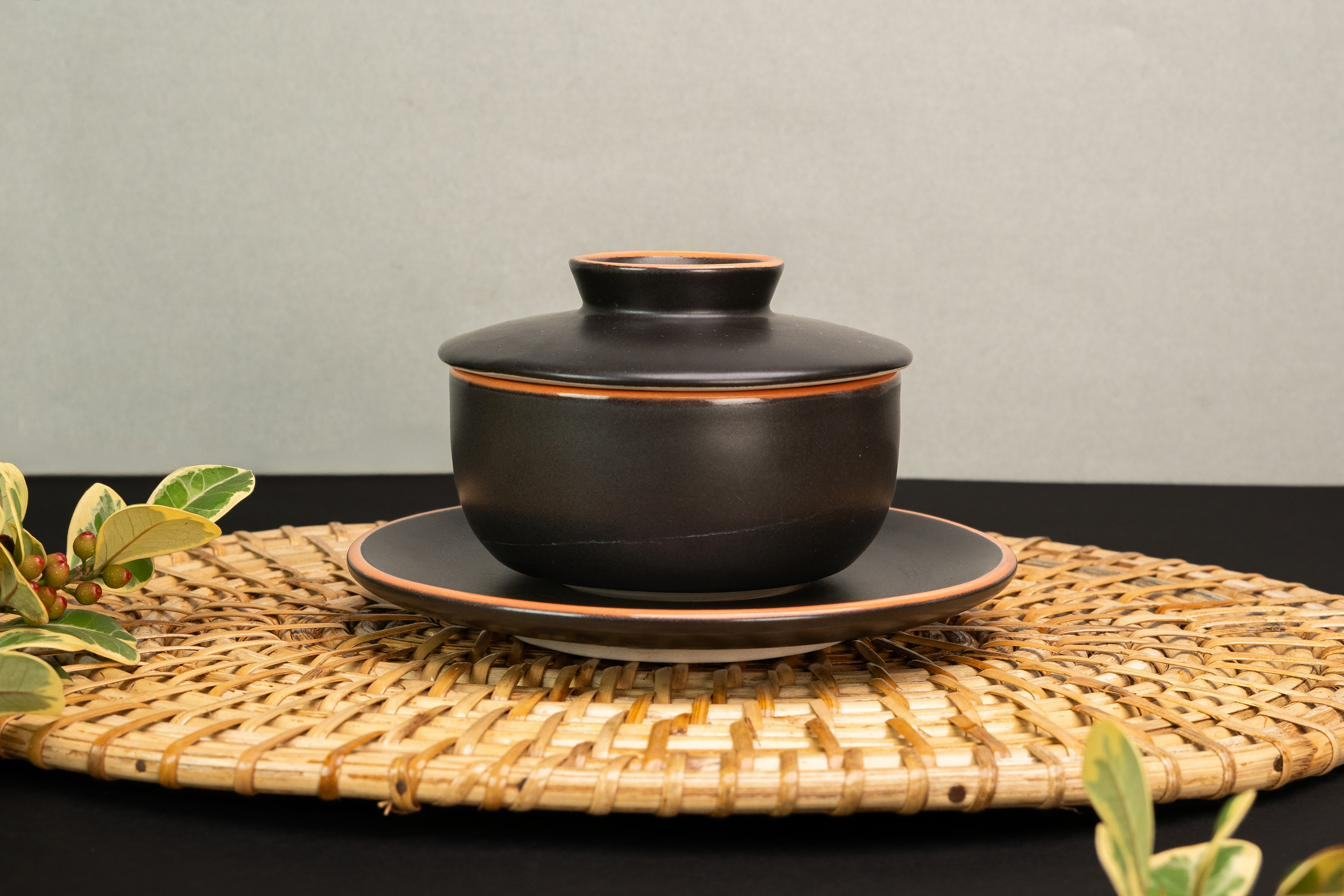 Black stoneware teapot on a woven mat
