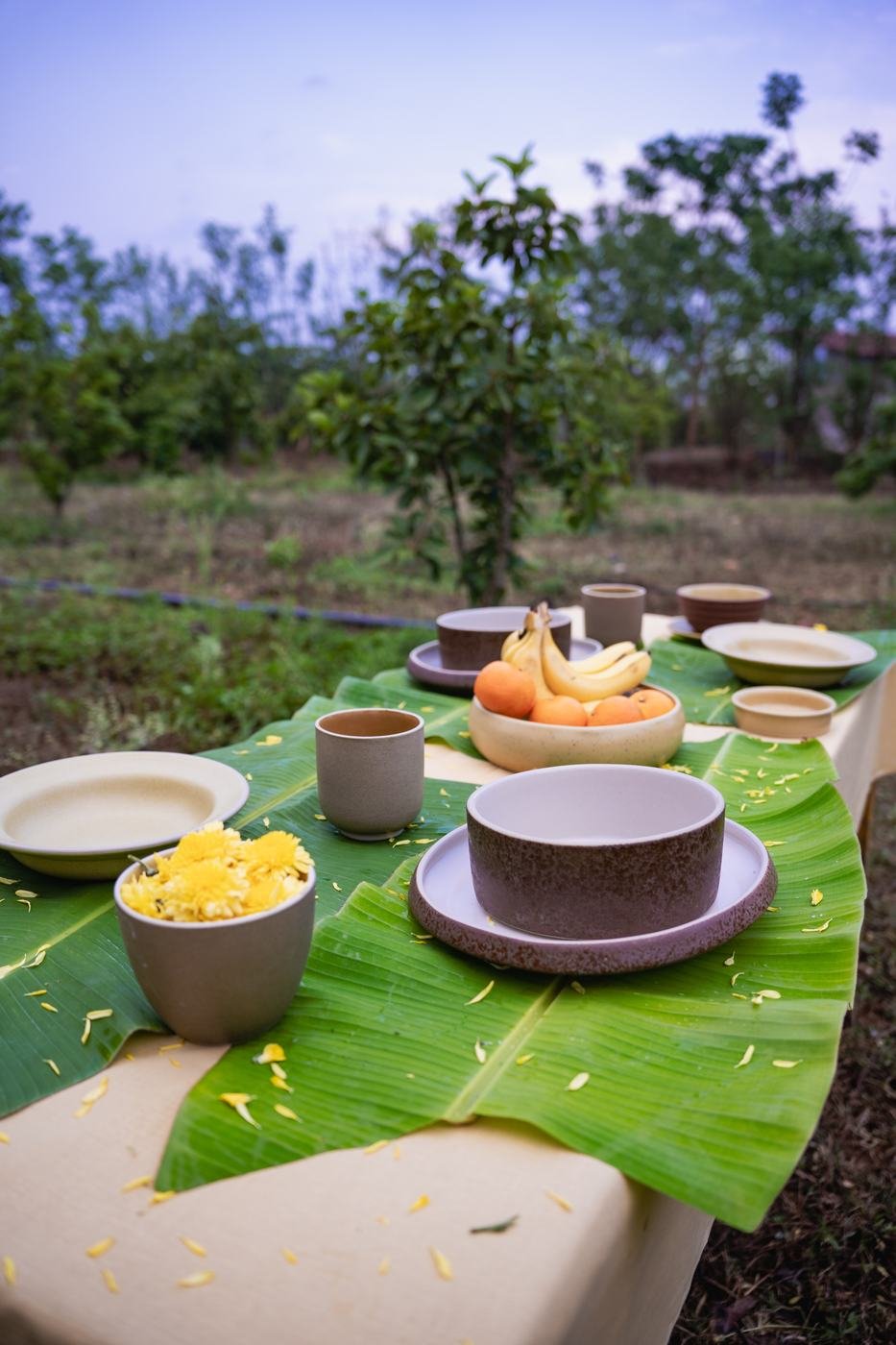 Nugu stoneware bowls and plates set on banana leaves for a restaurant-style meal